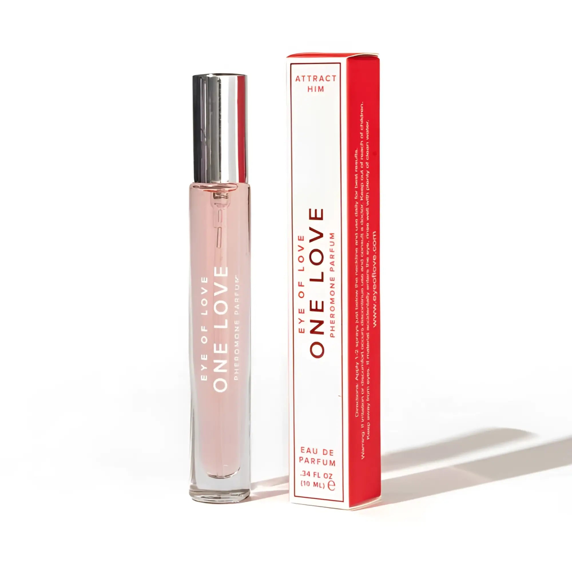 A sleek transparent glass rollerball perfume bottle with silver cap and pink liquid labeled eye of love pheromone parfum next to red and white box
