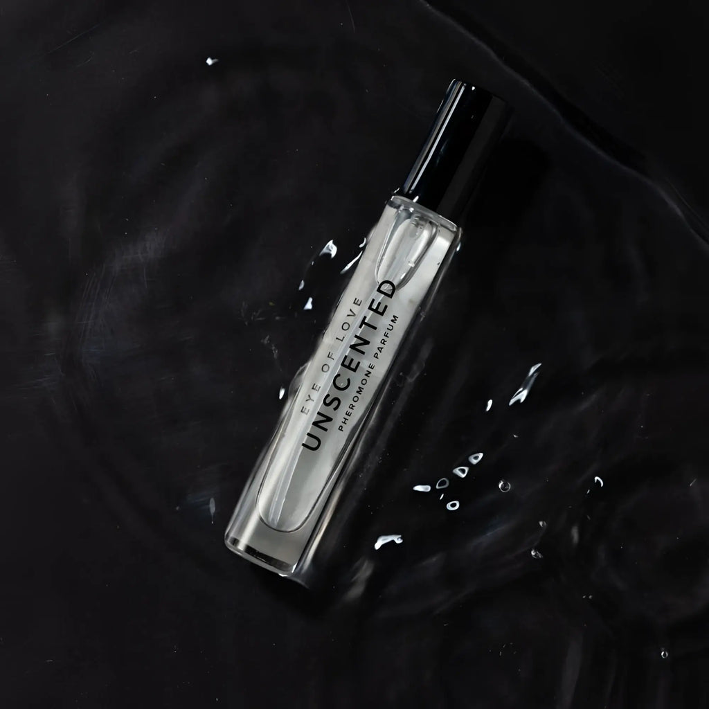 A sleek transparent glass bottle of eye of love unscented pheromone body spray with black cap and minimalist white label