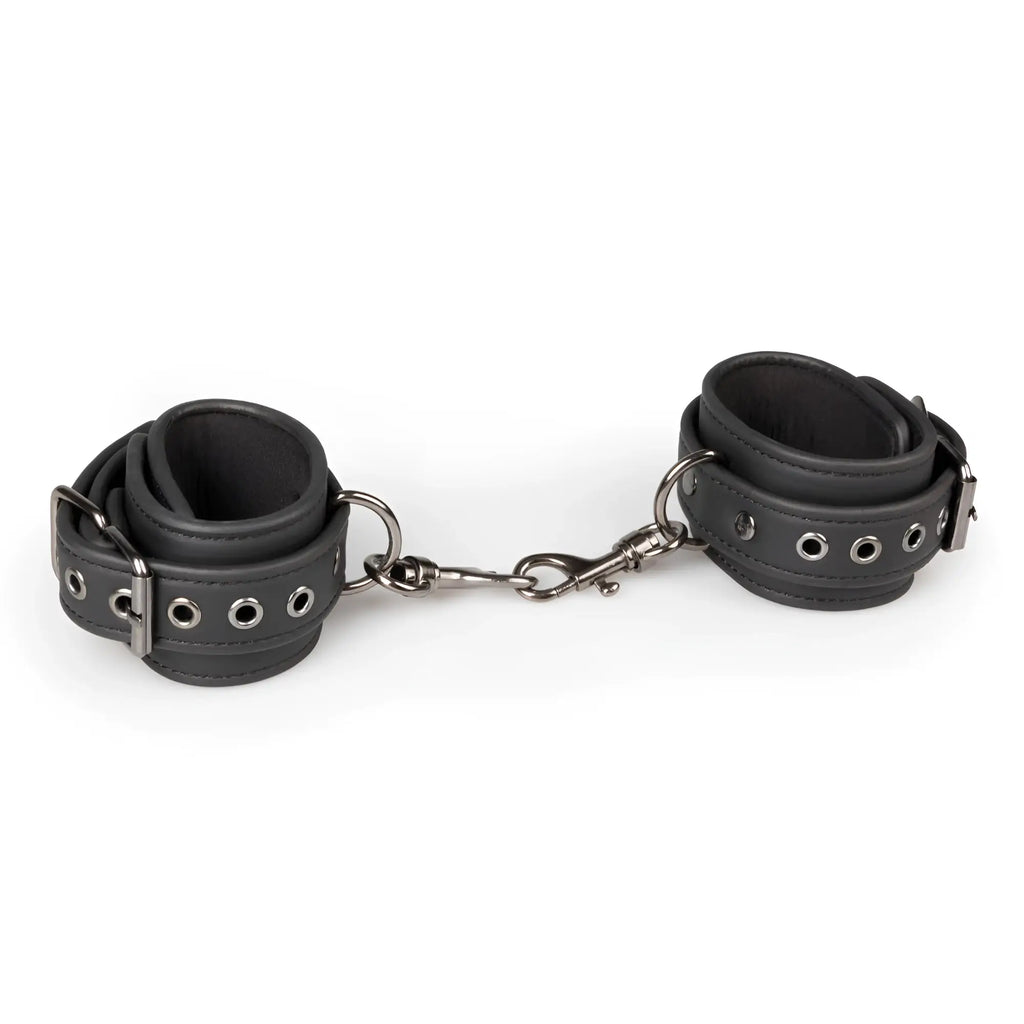Black leather wrist cuffs connected by metal chain from fetish collection ankle cuffs black set