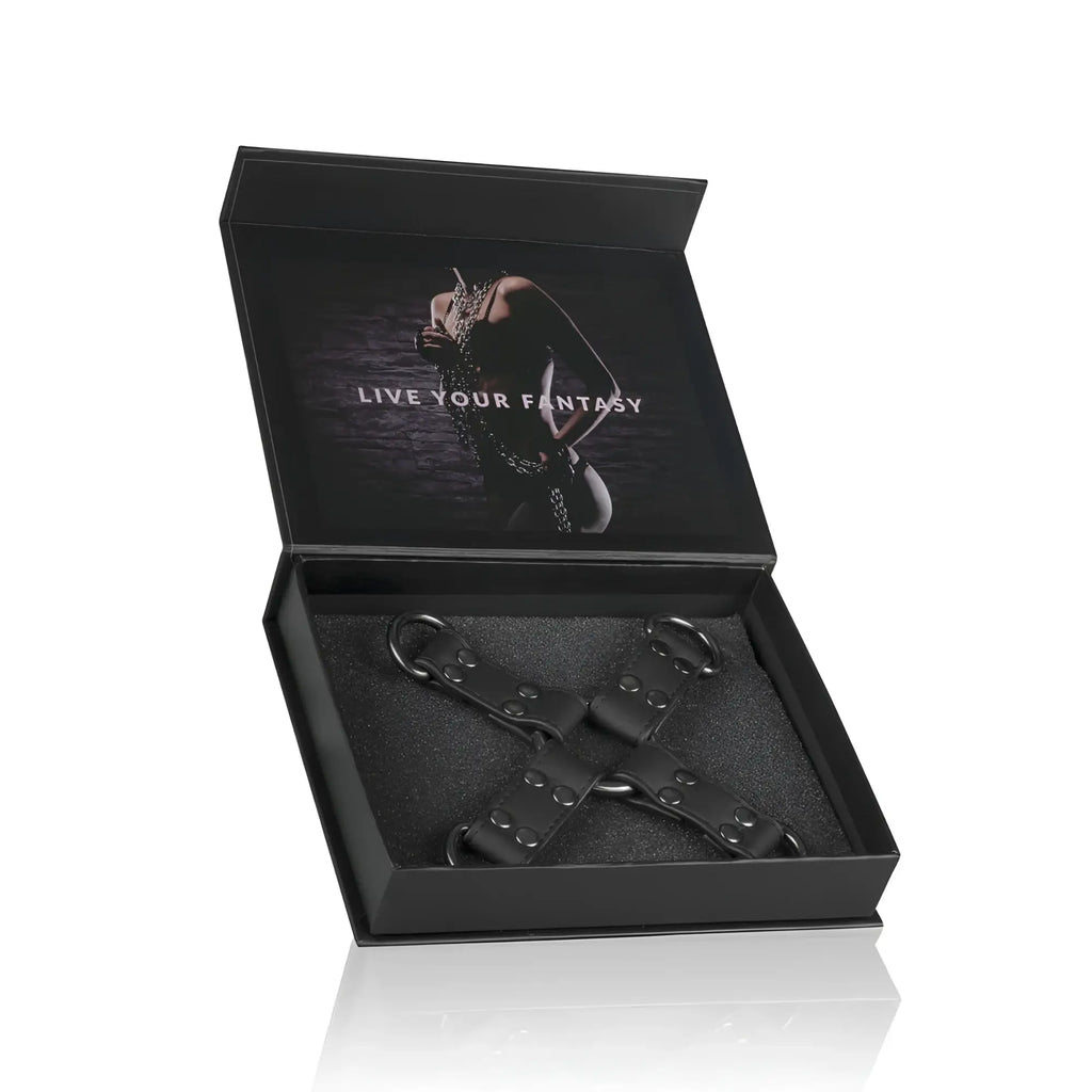 Black leather x-shaped restraint harness with metal d-rings and rivets in a sleek black gift box from Fetish Collection Hogtie Black