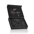 Black leather x-shaped restraint harness with metal d-rings and rivets in a sleek black gift box from Fetish Collection Hogtie Black