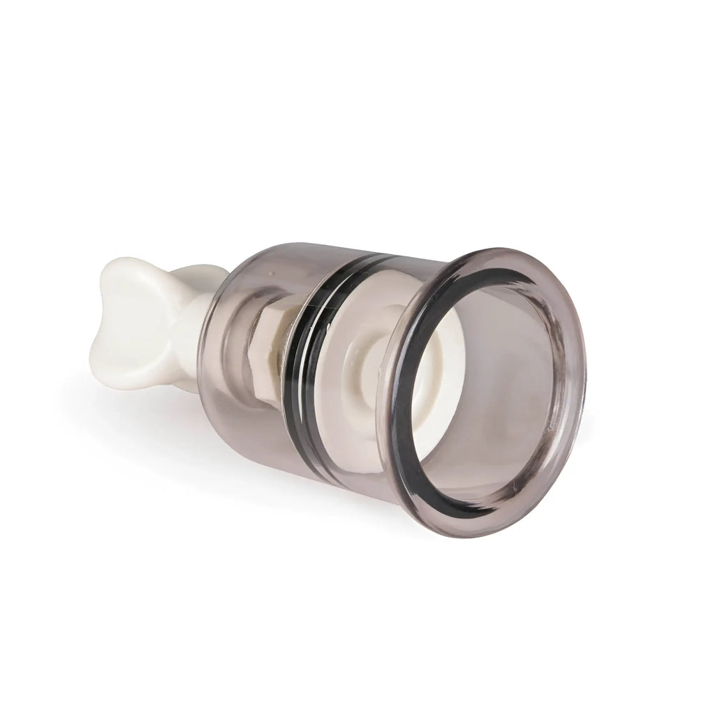 Transparent gray glass nipple and clit suction cup with white plastic handle and internal mechanism from fetish collection