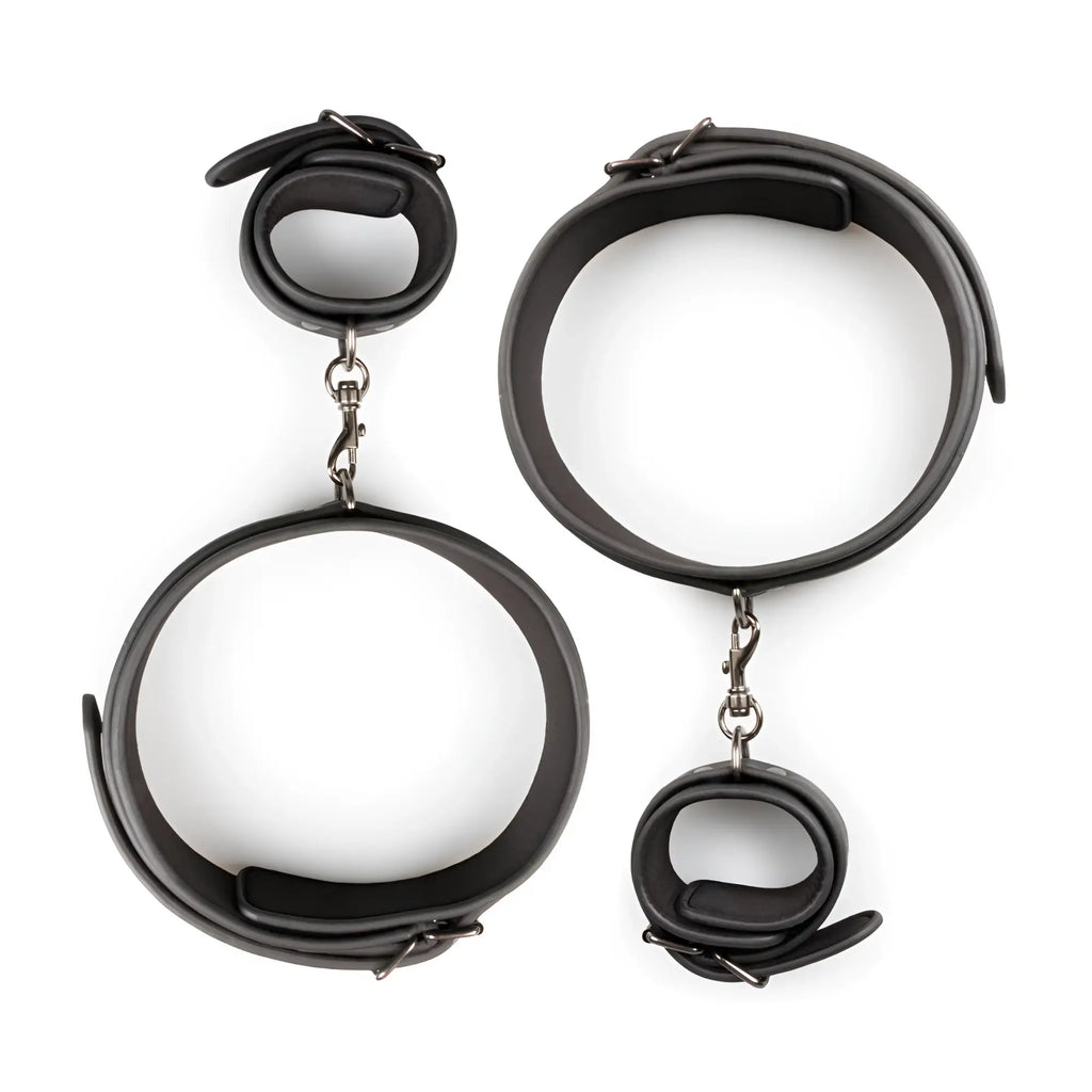 Fetish collection thigh and wrist cuff set featuring black leather handcuffs with silver-toned metal clasps and adjustable straps