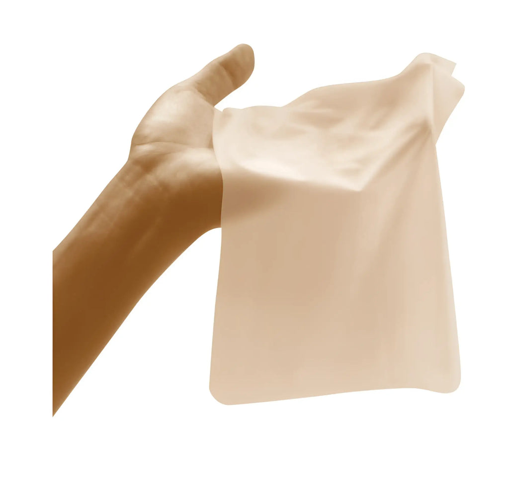 A translucent beige silicone sheet from four seasons sheer dams 100 pc mixed box held gently in a hand