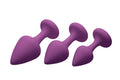 Three purple silicone anal plugs of varying sizes arranged diagonally from frisky purple pleasures 3 pc silicone anal plugs