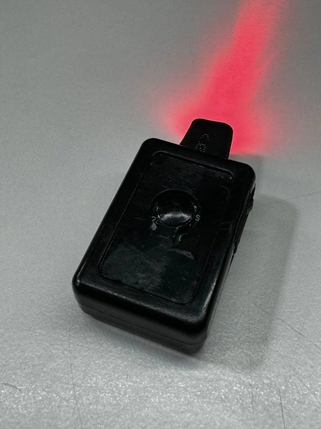 Black plastic garrison hat battery laser pointer emitting a red beam for precision pointing and presentations