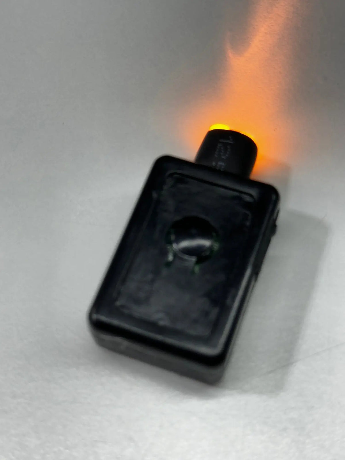 Black rectangular garrison hat battery with a glowing orange light at the top indicating power status