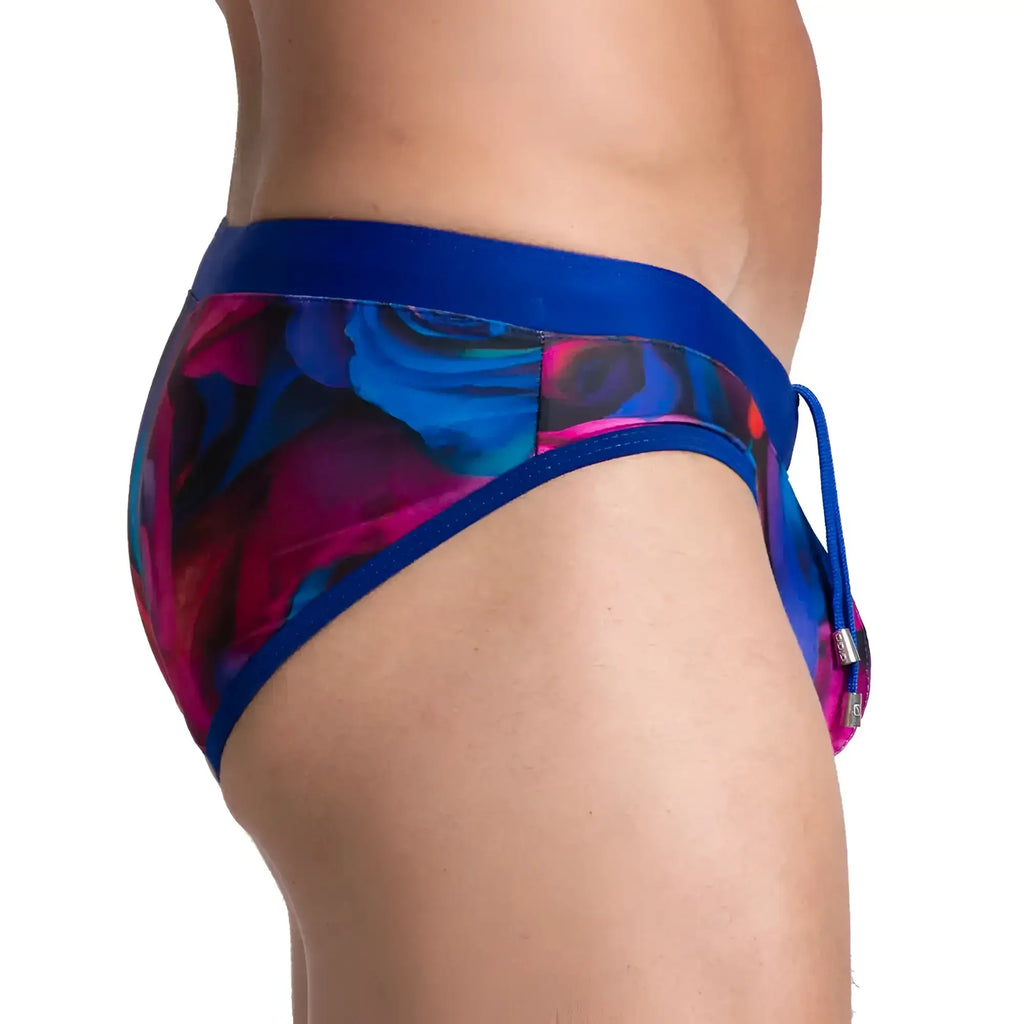 Gigo carnations swim brief featuring vibrant blue and magenta floral patterns with a solid royal blue waistband