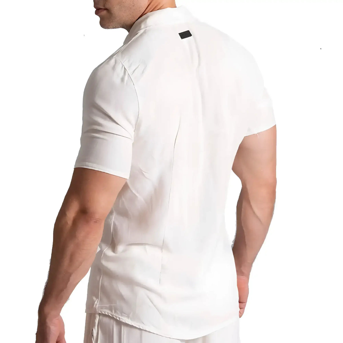 White short-sleeved collared gigo chalis beige shirt with subtle black tag at neckline made from breathable fabric