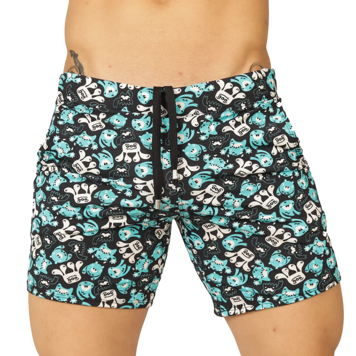 Black swim trunks from gigo comics beachwear with teal and white cartoon monsters featuring goo on chests