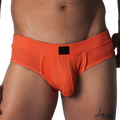 Bright orange textured micro-mesh brief with a supportive pouch and a solid black logo tag on the center waistband.