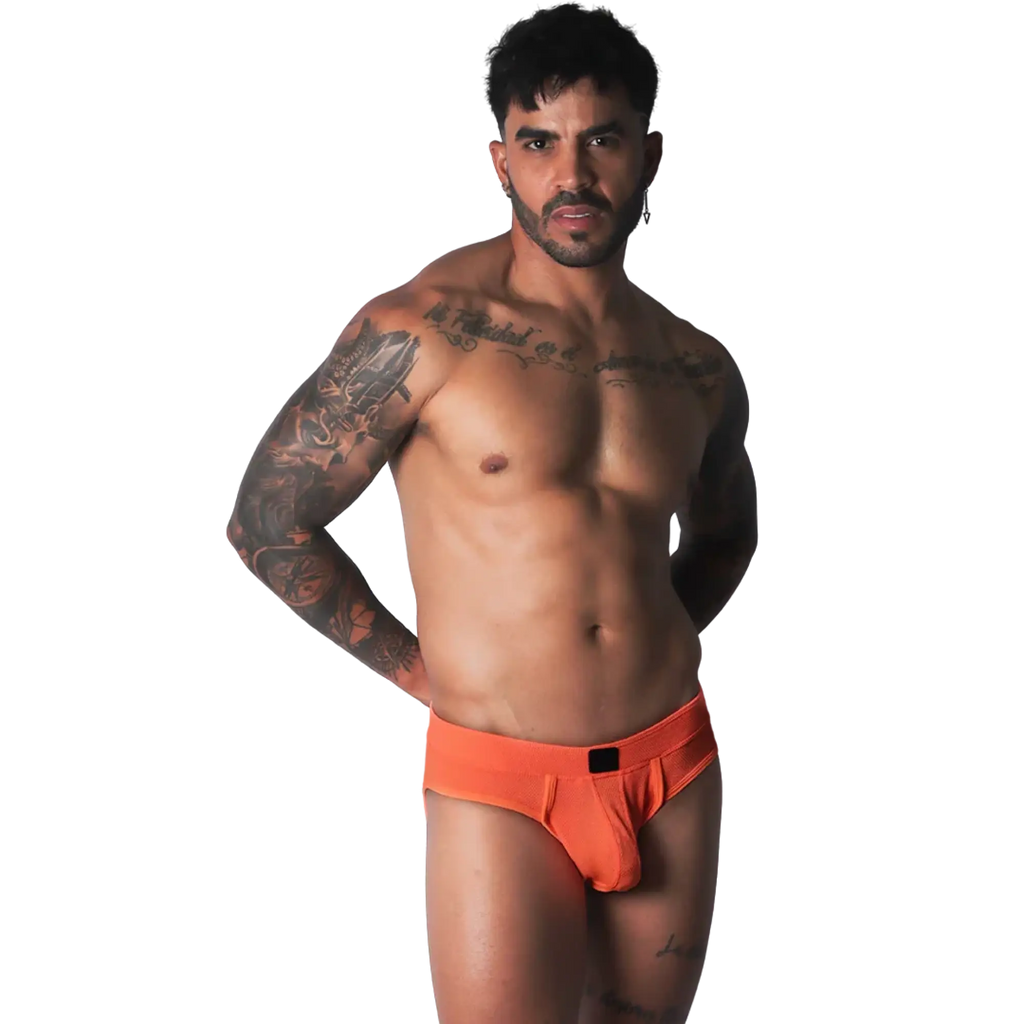 Bright orange athletic mesh jockstrap with a black logo patch on the center waistband, worn by a muscular man.