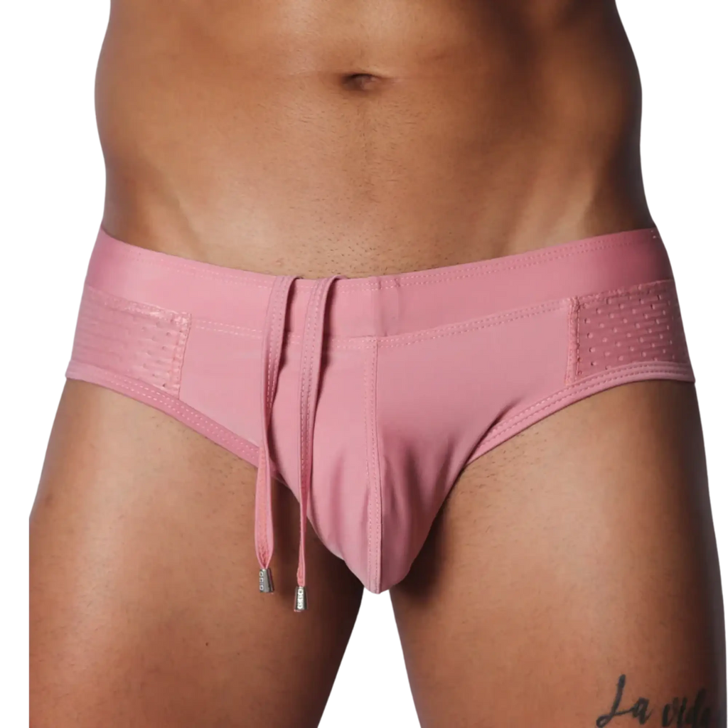 Dusty pink swim brief with a smooth center, side mesh panels, and hanging decorative drawstrings with silver tips.