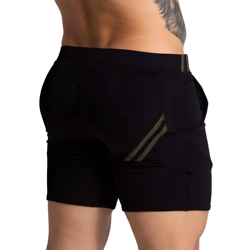 Black textured athletic shorts with olive green diagonal stripes on back pocket and waistband shown from back side
