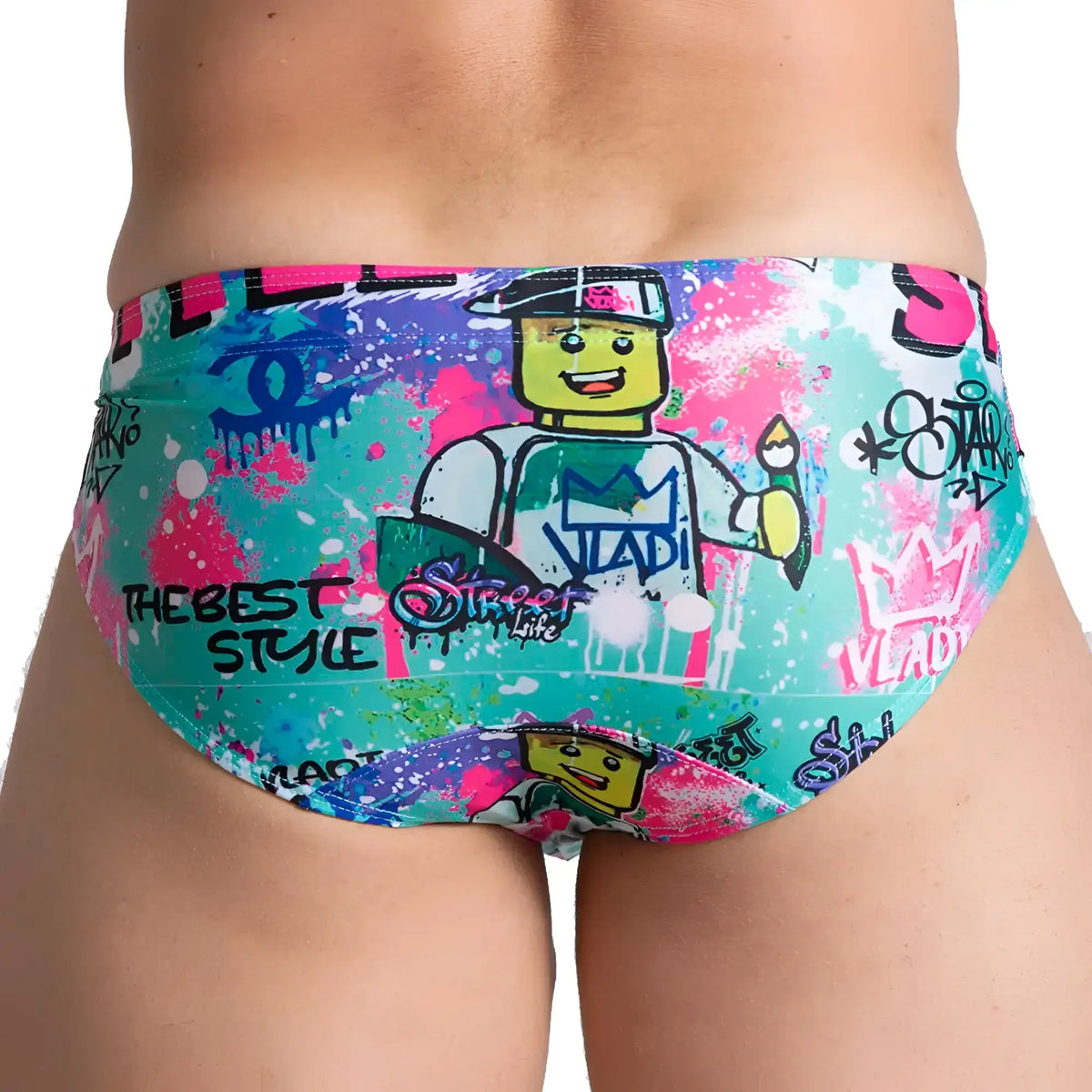 Vibrant turquoise gigo figure swim brief featuring playful lego character with bold pink blue and green graffiti splatters