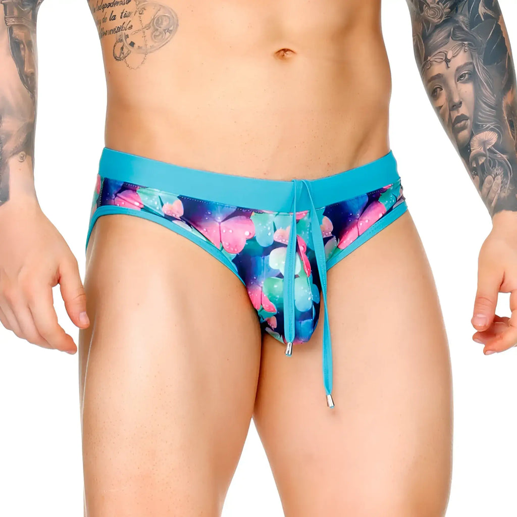 Gigo Flowers swim brief in vibrant turquoise with bold pink and blue butterfly print on a dark background