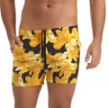 Black swim trunks with vibrant yellow and white floral pattern and drawstring waistband from Gigo Flowers Yellow Beachwear