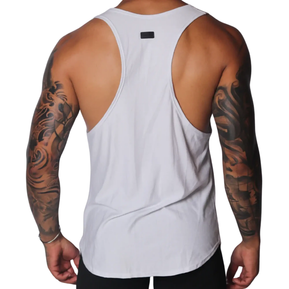 White racerback tank top with deep-cut sides, a curved hem, and a small black logo patch at the upper back.