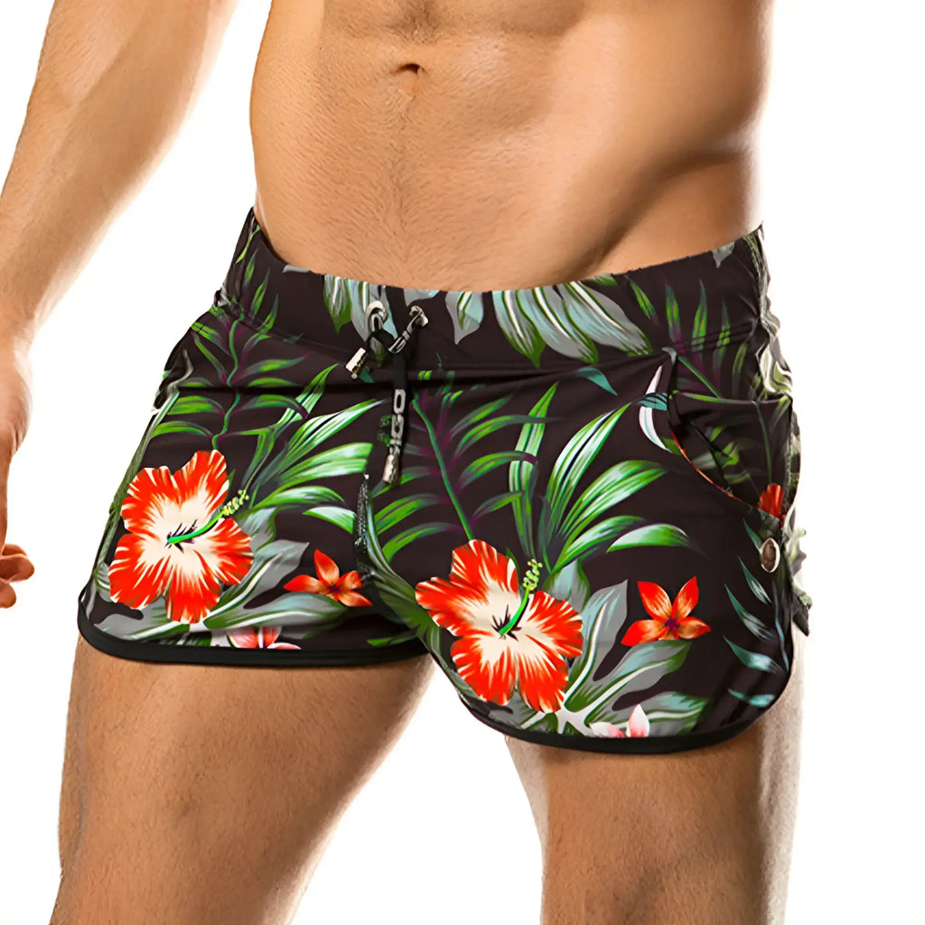 Black swim trunks from gigo garden beachwear with vibrant red hibiscus flowers and green tropical foliage print