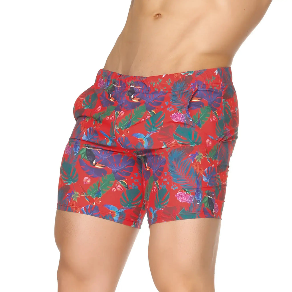 Vibrant red Gigo Macaws swim trunks with bold tropical purple green and pink leaf and bird print for beachwear