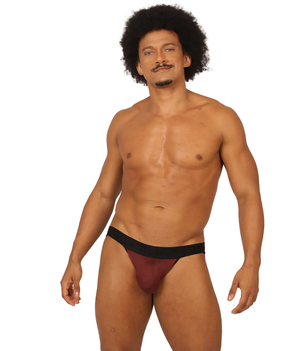 A man wearing a snug fit gigo mix wine jockstrap in maroon and black showing the front side of the product