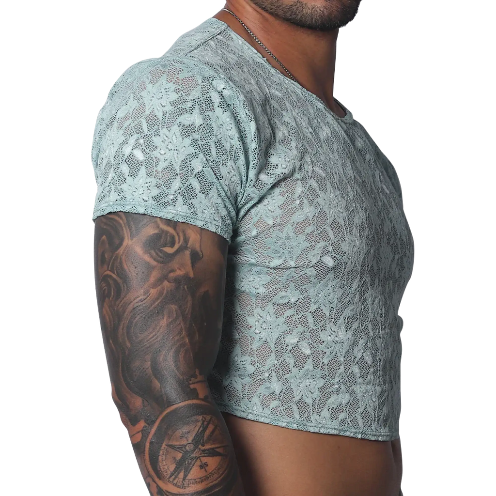 Sheer aqua blue floral lace crop top with short sleeves and a crew neck, worn by a man with arm tattoos.
