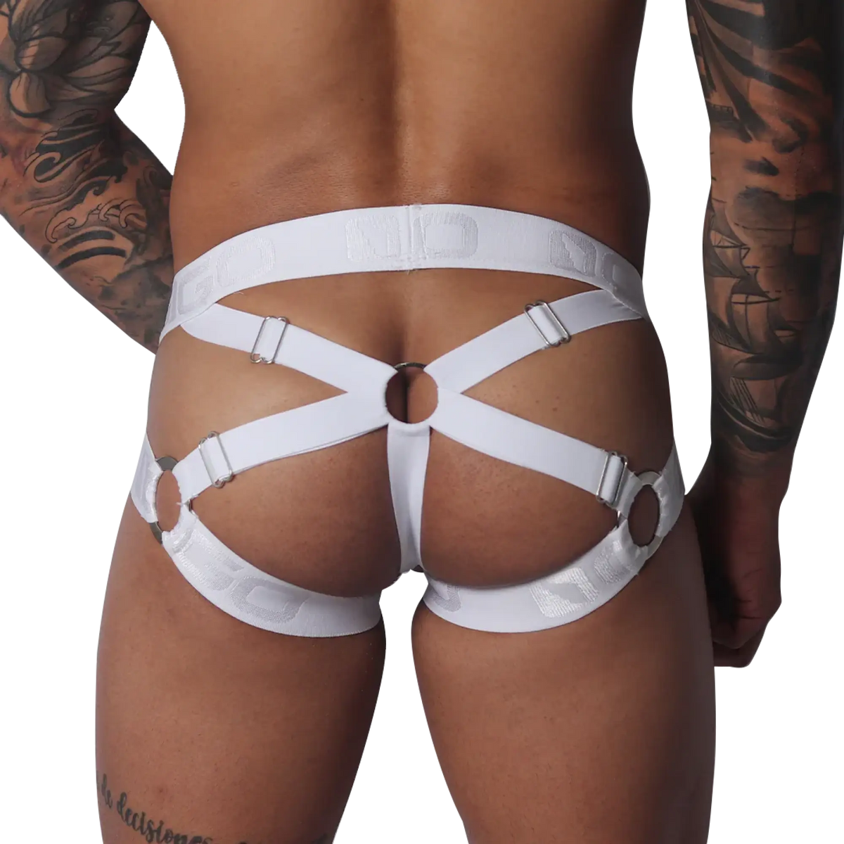 White jockstrap with elastic straps, silver metal rings, and adjustable sliders on a tattooed male model.
