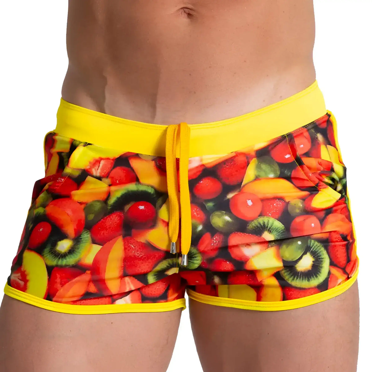 Bright yellow gigo salad beachwear swim trunks with vibrant sliced strawberry kiwi and mango print on dark background
