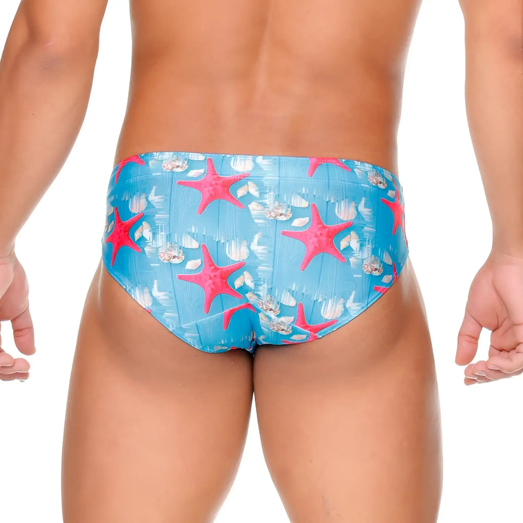 Gigo sea swim brief featuring bright pink starfish and white seashell patterns on vibrant blue swim trunks material