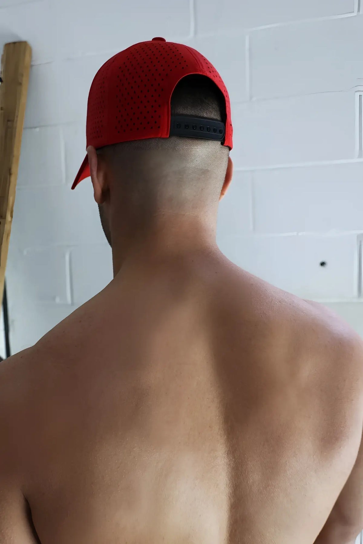 Red perforated baseball cap with black adjustable strap showing the back side from gymnetixxx hat collection