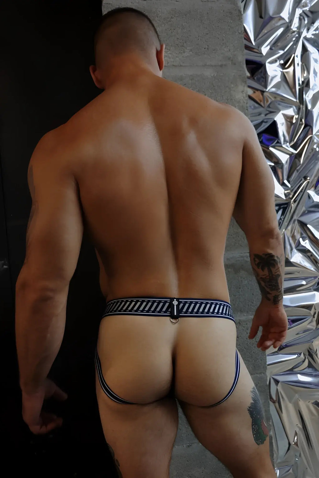 Back view of gymnetixxx jock navy blue and white striped briefs with central metal ring and mesh fabric detail