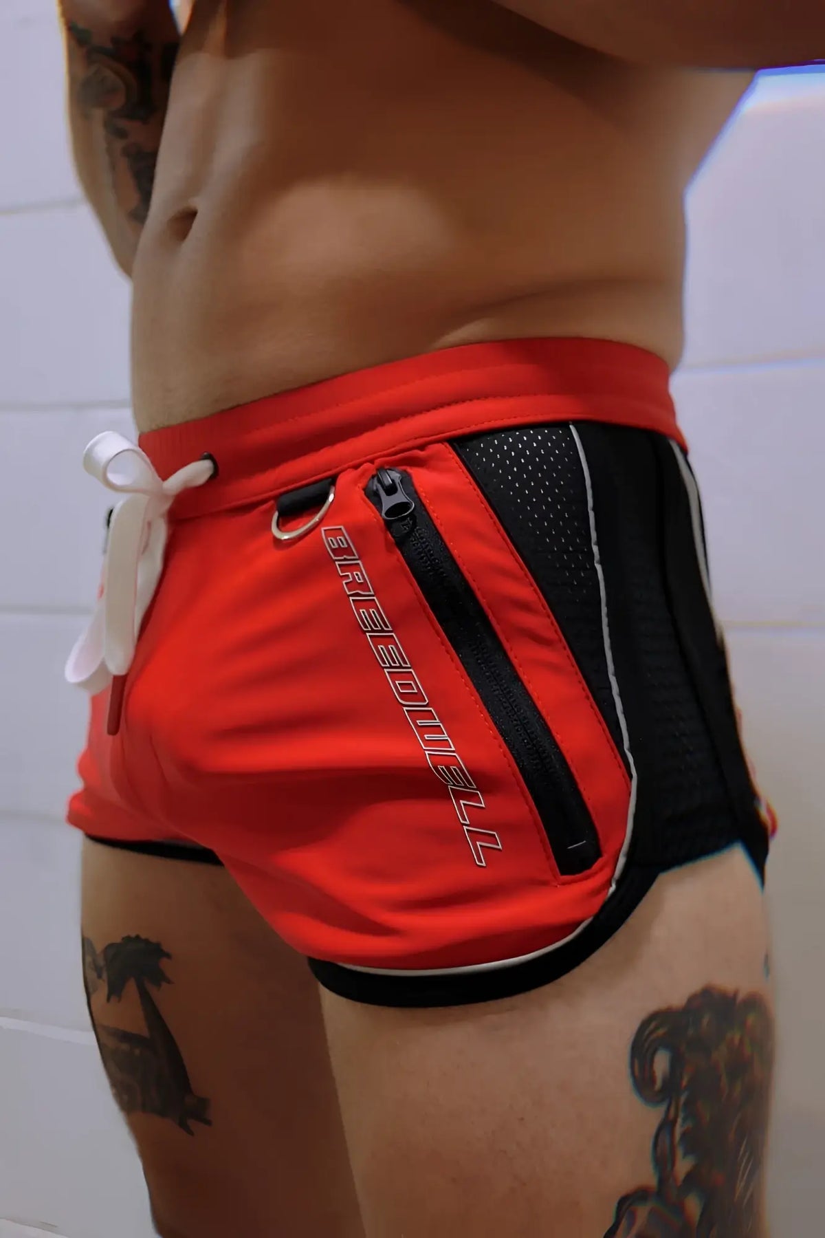 Red and black Gymnetixxx athletic shorts with white drawstring and silver griffin logo lettering along the side