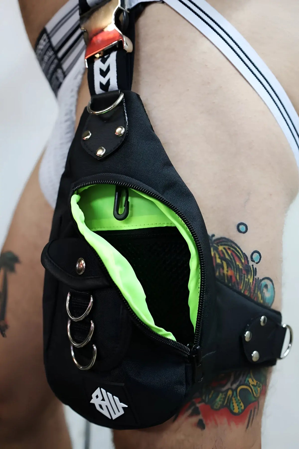 Black hustler leg bag with neon green interior lining silver-toned metal hardware and white front logo