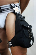 Black hustler leg bag with silver metal rings and white logo patch in tactical style for hands-free carrying
