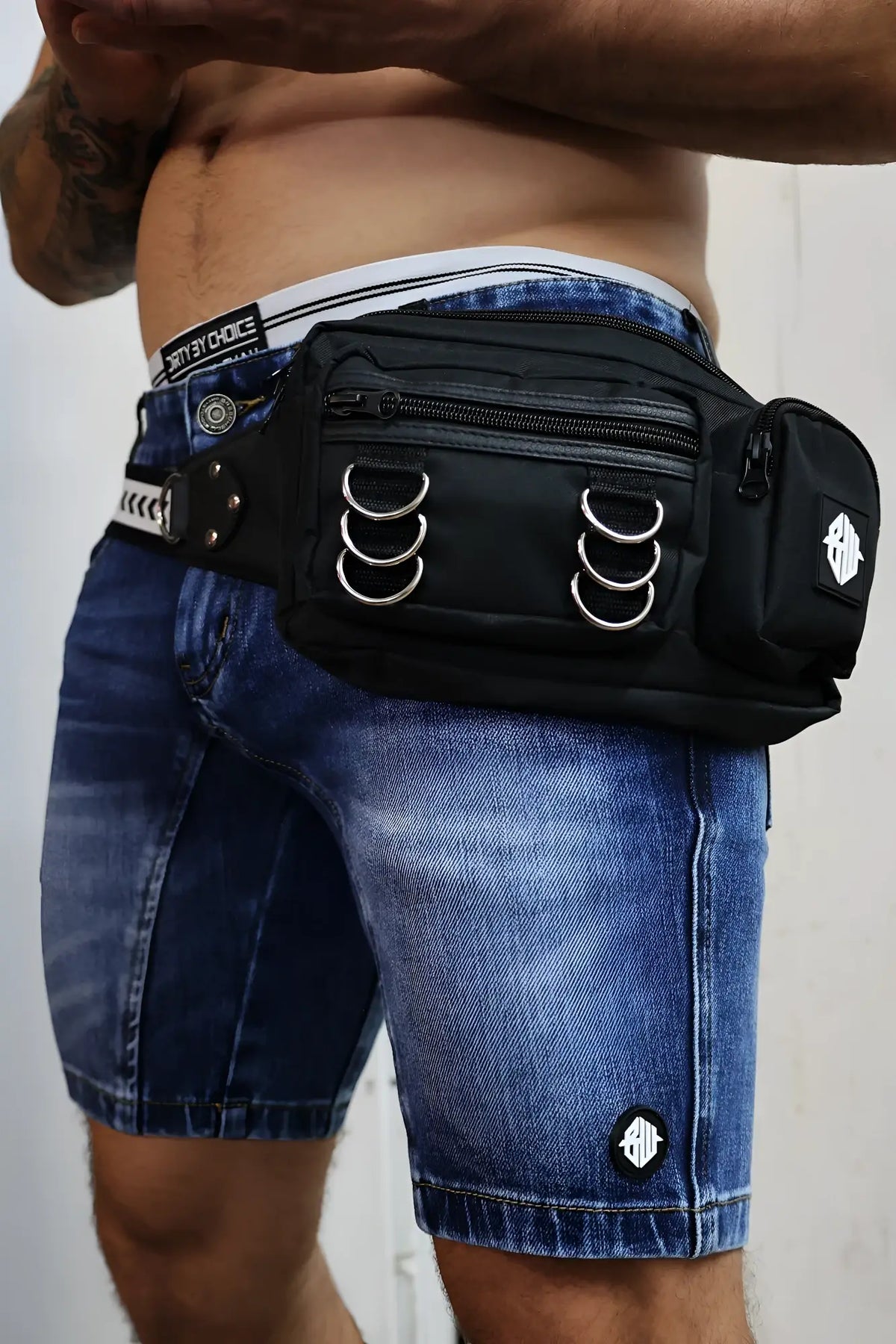 Black hustler waist pack with tactical style silver metal rings zippers and logo patch on the side