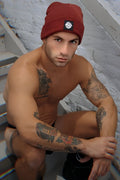 A maroon knitted Iconixxx beanie with a black rectangular logo patch on the front for cold weather use
