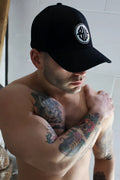 Black baseball cap with white circular logo featuring stylized lettering on the front called illuminator icon hat