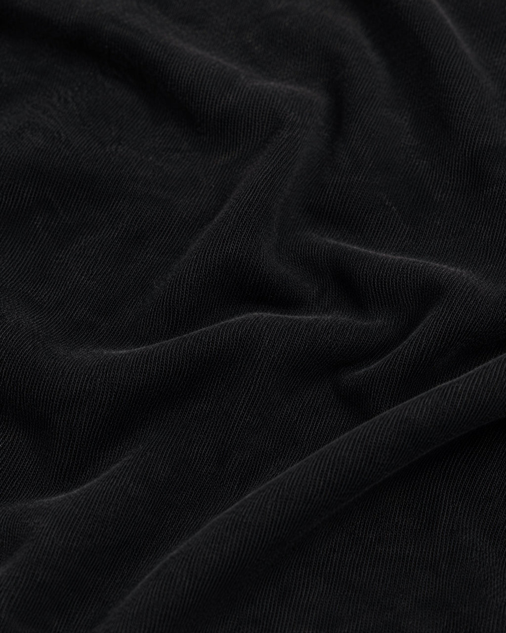 Close-up of soft, matte black fabric with visible fine-knit texture and elegant folds.