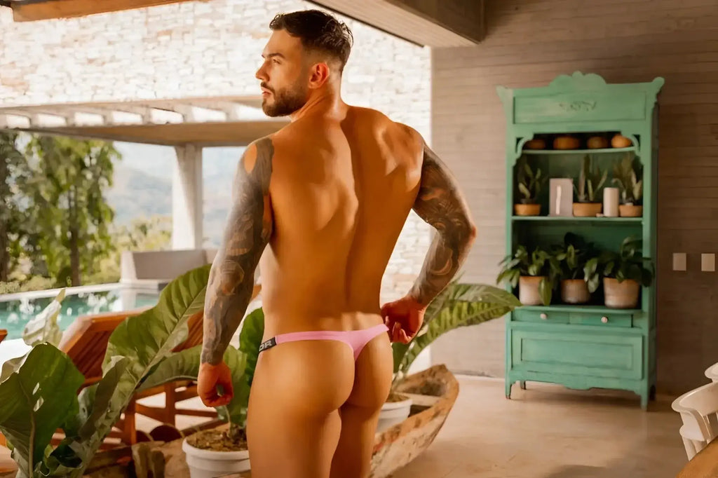 Lifestyle shot of a man wearing JOR 2357 Eros thong in pink, showing a back view of the underwear.
