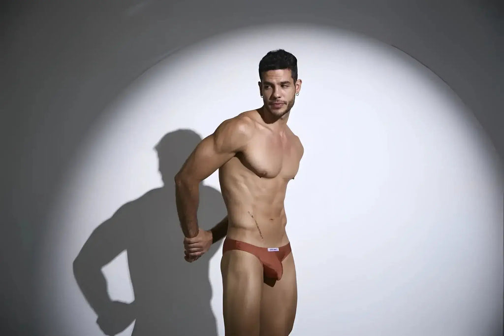 A sleek rust-coloured men’s brief with minimalist design and small white logo on waistband.