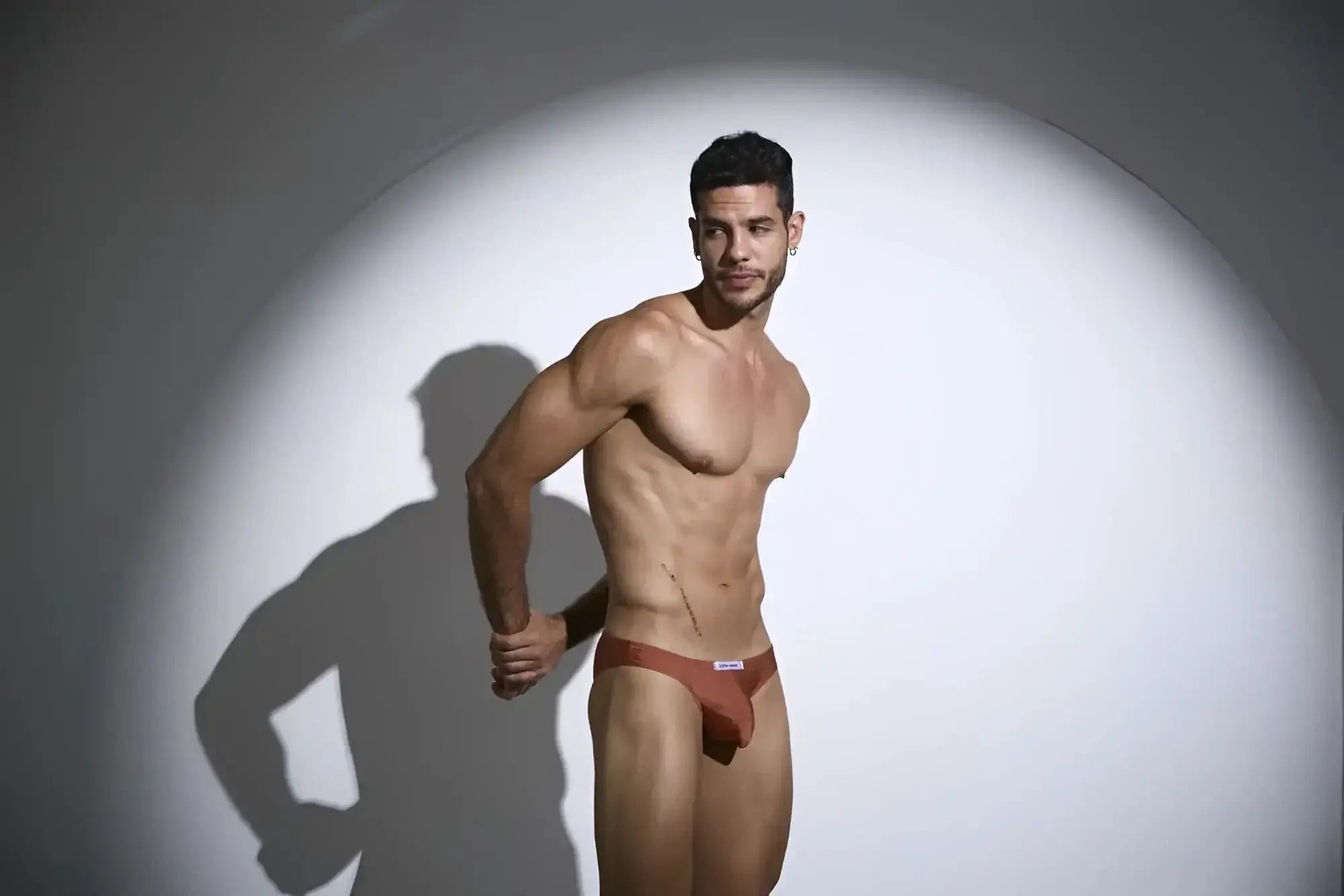 A sleek rust-coloured men’s brief with minimalist design and small white logo on waistband.