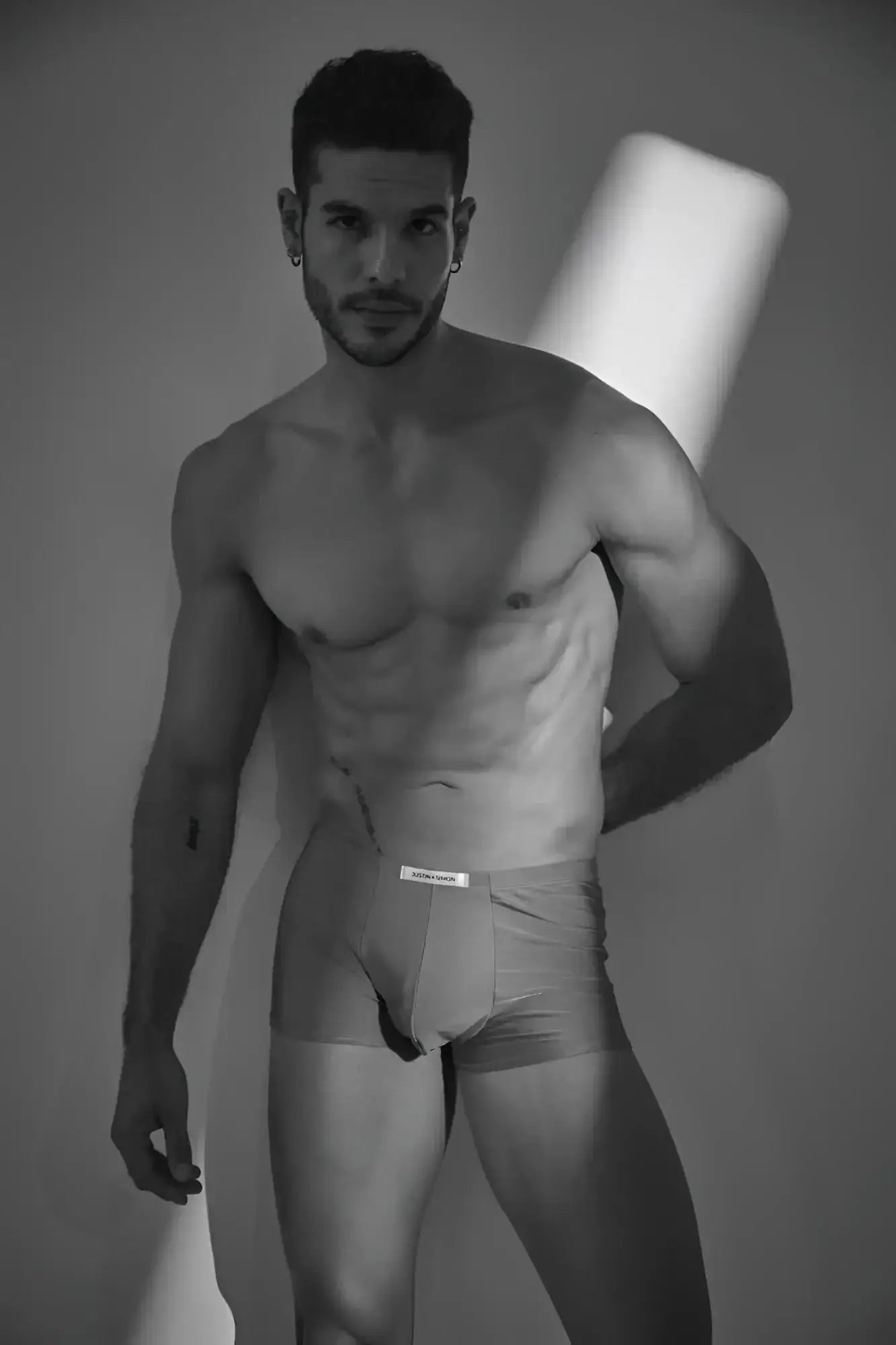 The man is wearing light-colored Calvin Klein classic boxer briefs in metal green with a visible waistband logo