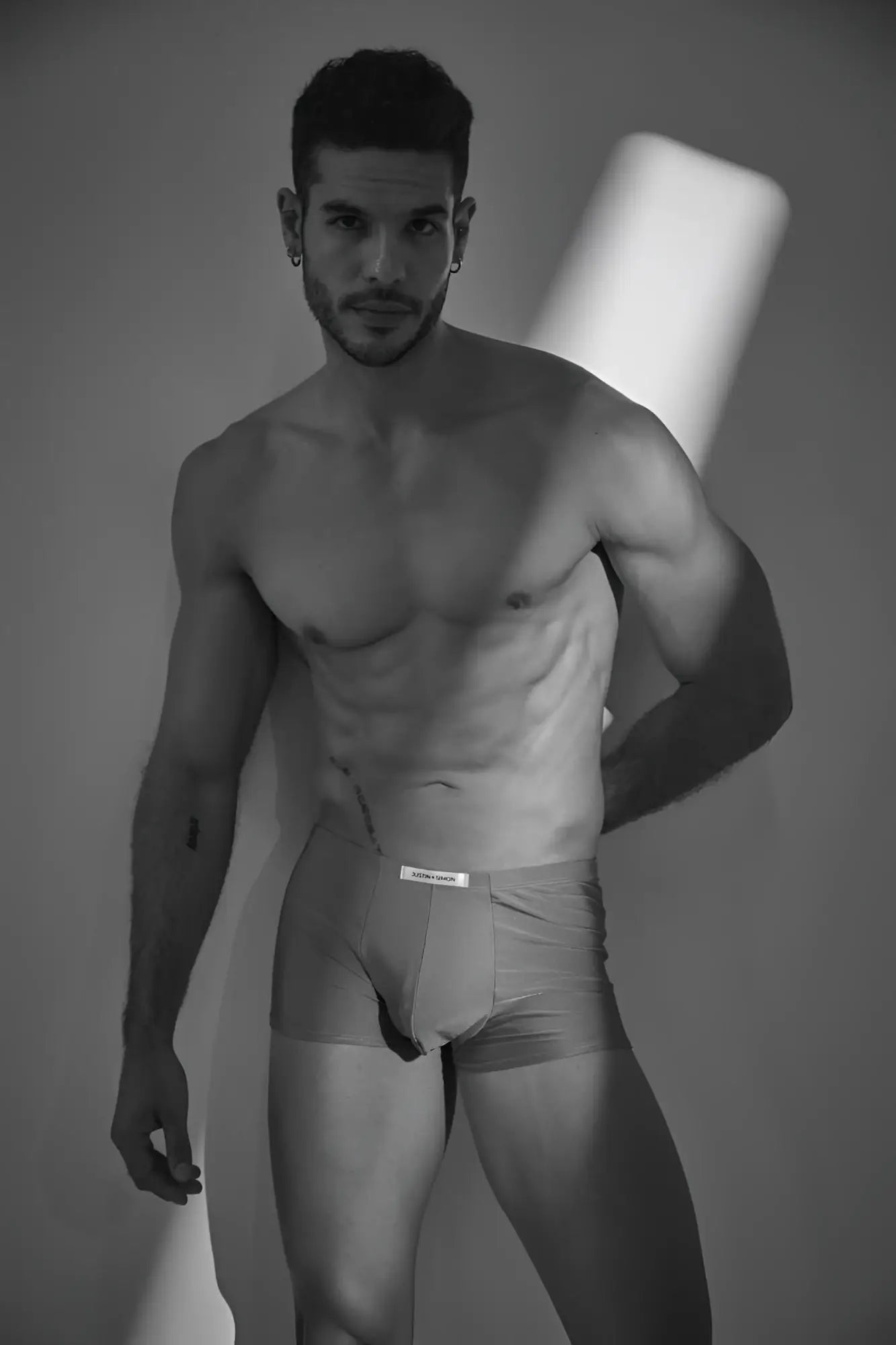 The man is wearing light-colored Calvin Klein classic boxer briefs in metal green with a visible waistband logo