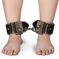 Lovetoy Rebellion Reign black and brown leather ankle cuffs with love pattern connected by metal chain