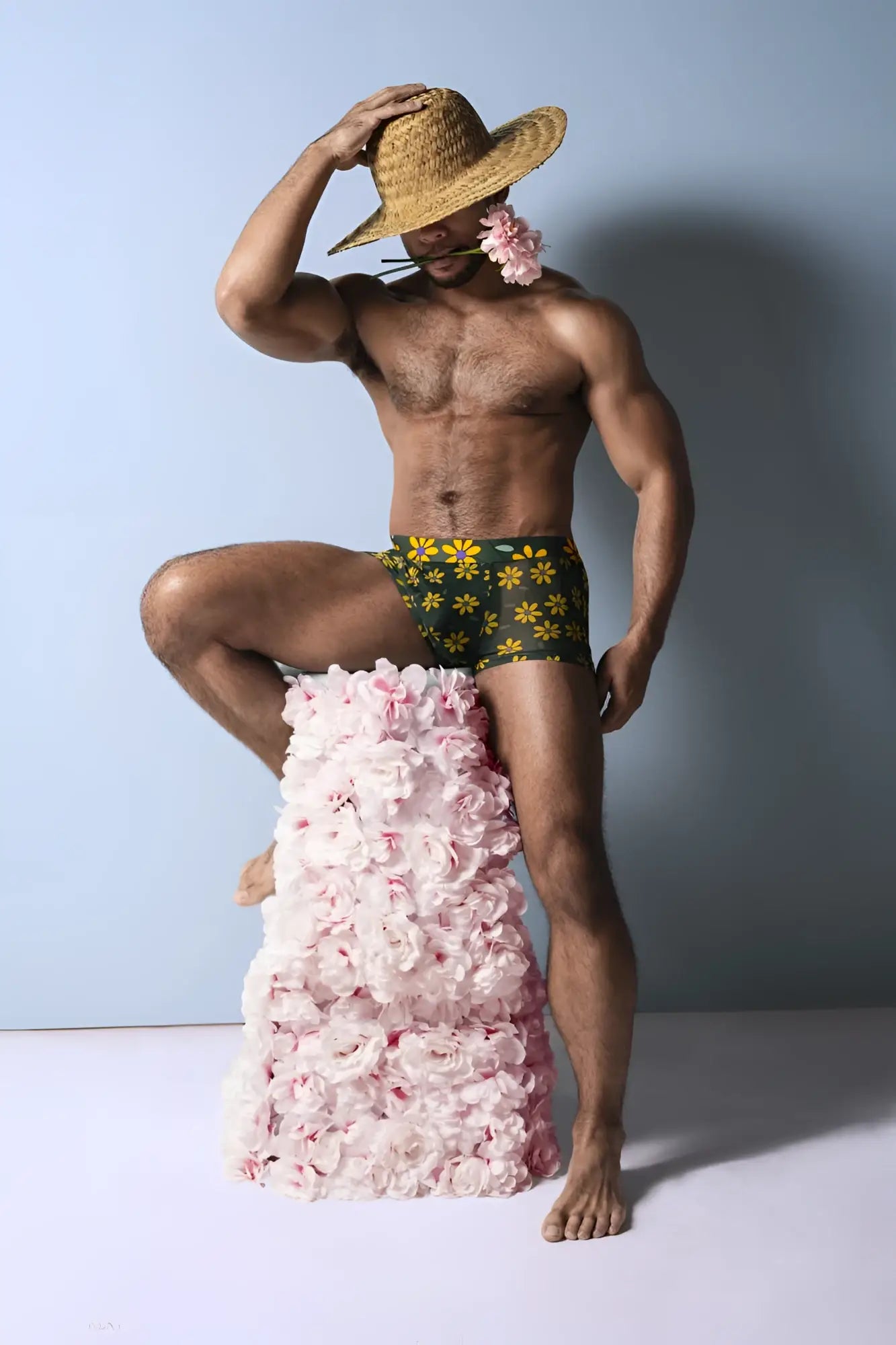 A man wearing male power petal power pouch shorts in green and yellow daisy print swim trunks