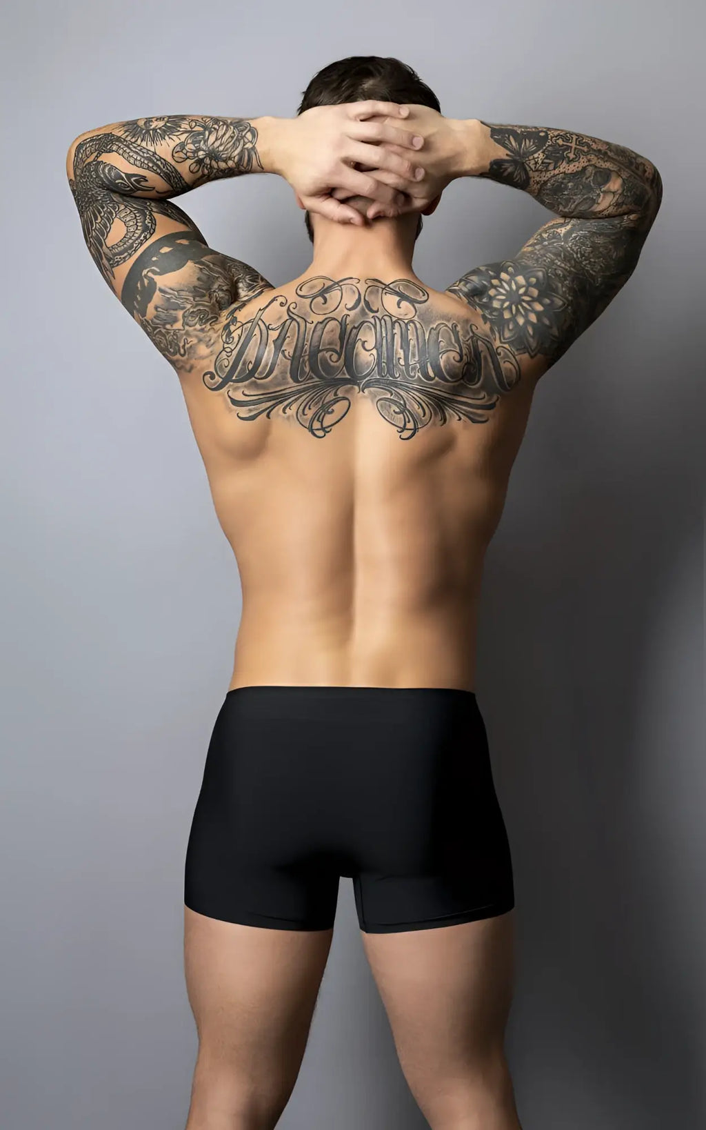 A man wearing male power 154-300 hot mesh pouch short black-red showing extensive black tattoos on back side