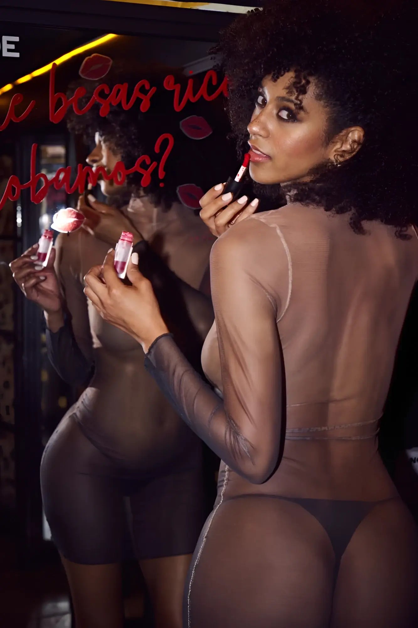 A woman holds red lipstick wearing sheer black Mapale 40000 bodysuit dress in midnight shadow color