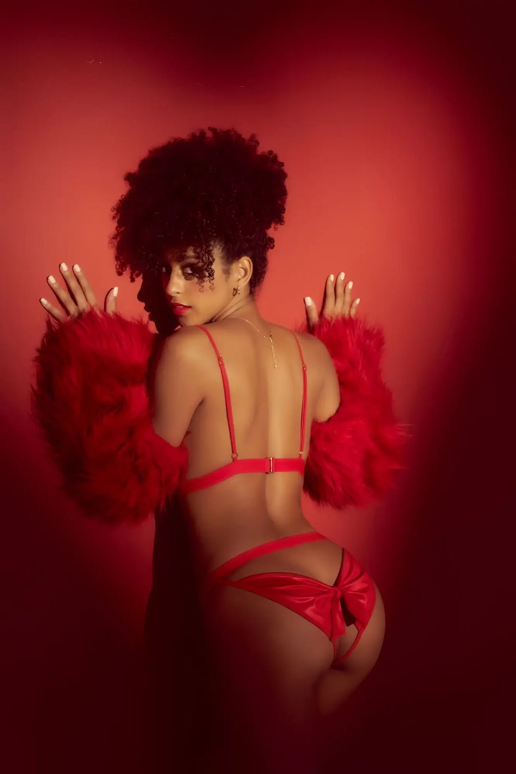A woman wears a vibrant red satin lingerie two piece set with thin straps and a feathered arm accessory by Mapale 8901