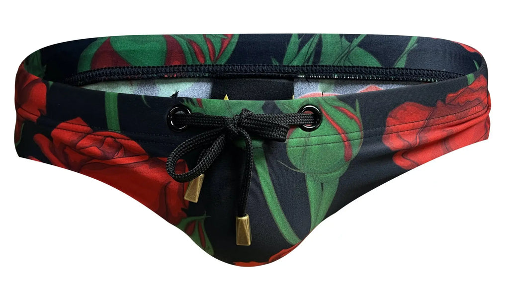 Black marcuse amour bikini swimwear trunks with vibrant red rose green leaf pattern and gold-tone metal drawstring accents