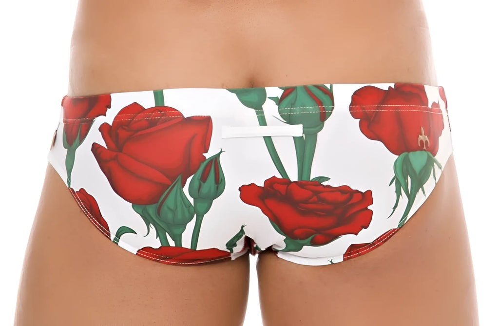 White marcuse amour bikini swimwear trunks with bold red rose pattern and green stems for swim and beachwear